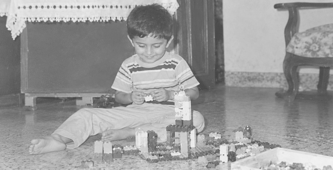 Pranay as a child, sitting on the floor building with LEGO